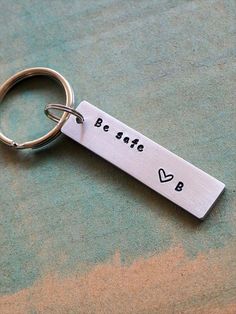 a metal keychain with the words be safe and heart in black on it