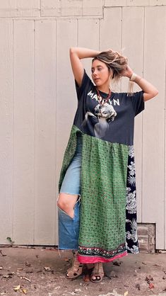 a woman standing in front of a white wall wearing a black shirt and green skirt