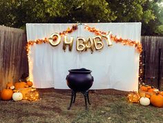 an outdoor baby shower with pumpkins on the ground and lights around it, along with a large black caulder