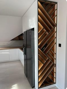 a modern kitchen with white cabinets and wood accents on the walls, along with a black refrigerator freezer