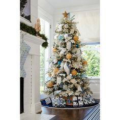 a decorated christmas tree in the corner of a living room with blue and white decorations