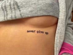 a woman's stomach with the words never give up tattooed on her lower back