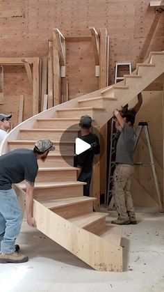 three men are working on some stairs in a building that is being built with wood