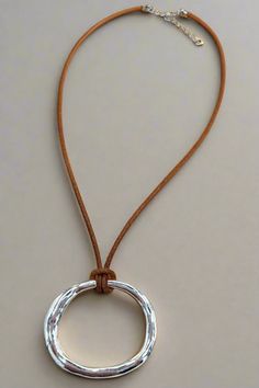 This Rippled Oval Pendant Short Thick Leather Cord Necklace is a stylish accessory that combines a trendy design with durability. Made with a thick leather cord and a unique rippled oval pendant, this necklace is perfect for everyday wear or special occasions. Upgrade your outfit with this versatile and eye-catching necklace. Details:- Genuine Leather Cord- Adjustable by 2"- Simple Hammered Oval Pendant Dimensions:- Approx. 16" Length- Extendable by 2"- Pendant Size: 1.5" x 2" Short And Thick, Leather Cord Necklace, Leather Corded Necklace, Loose Fitting Tops, Oval Pendant, Cord Necklace, Stylish Accessories, Vintage Accessories, Leather Cord