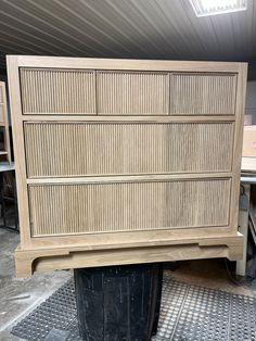 a large wooden dresser sitting on top of a trash can in a room with metal grates