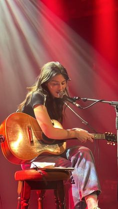 a woman sitting on top of a wooden chair next to a microphone and an instrument