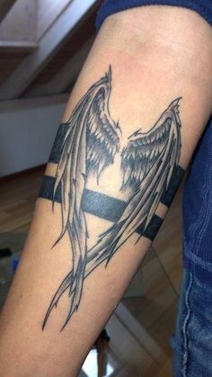 a man with a black and grey tattoo on his arm that has an angel wing