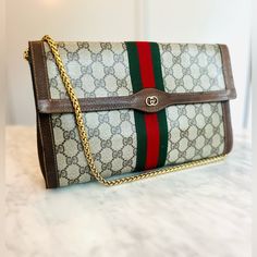 Authenticated Gucci Sherryline Clutch Bag. Front Flap With Fastener. Gg Monogram Coated Canvas With Sherryline Webbing. Comes With An Unbranded Gucci Style Strap Or A Long Gold Chain If You Prefer. Can Be Customized With D Rings To Add Strap Or A Chain Of Your Choice. This Bag Has A Very Practical Size Of 11.5” X 7.5” And Is In Excellent Vintage Condition. The Pouch Can Use As Clutch Or Easily Converted Into A Crossbody Bag. Clean, It Has A Ointment Smell Possibly Peppermint. Made In Italy. Reasonable Offers Only Questions? Leave A Comment Below! Gucci Clutch Bag, Gucci Clutch, Gucci Style, Gg Monogram, Vintage Clutch, Gucci Fashion, Clutch Pouch, D Rings, Gucci Bags