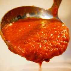 a spoon full of tomato sauce on top of a table