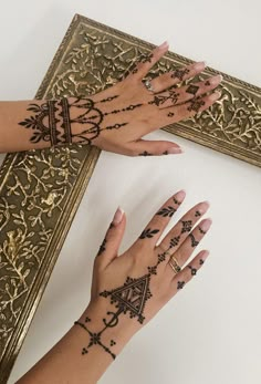 two hands with hendix on their palms are next to an ornate gold frame