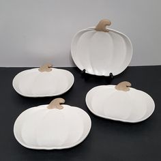 four white pumpkin shaped dishes sitting on top of a table