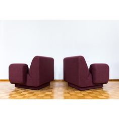 two purple chairs sitting on top of a hard wood floor next to a white wall