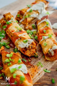 a wooden cutting board topped with pizza covered in sauce and green onions on top of it