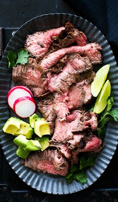 a plate filled with meat and vegetables on top of a wooden table next to an apple