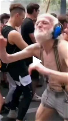 an old man dancing with headphones on in the middle of a group of people