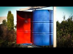 two blue and red barrels sitting next to each other in front of some bushes on a sunny day