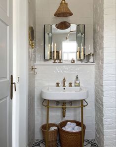 a white sink sitting under a bathroom mirror next to a basket filled with toilet paper