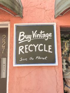 a sign that says buy vintage recycle save the planet on a pink building