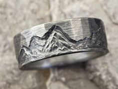 a silver ring with mountains engraved on it