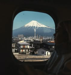 a man is looking out the window of a vehicle at a snow - capped mountain