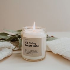 a white candle sitting on top of a table next to some towels and eucalyptus leaves