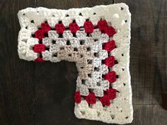 a crocheted red and white square on a wooden surface