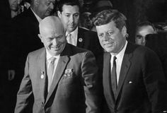 two men in suits and ties walking next to each other with one man wearing a suit