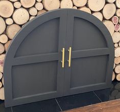 an arched wooden door sitting on top of a pile of logs