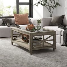 a living room with white couches and a coffee table in front of a window