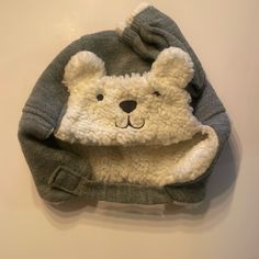 a white teddy bear wearing a gray and white knitted hat on top of a wall