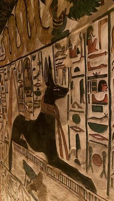 an egyptian wall painting with black dog in front of the hieroglyphics