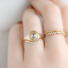 a woman's hand with two rings on it and one has a diamond in the middle