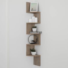 three wooden shelves with plants and pictures on them in the corner of a white room