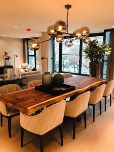 a dining room table with chairs and lights hanging from it's center point in front of a large window