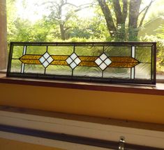 a stained glass window sitting on top of a window sill in front of a tree