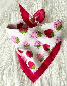 a bandana with strawberries on it is laying on a white furnishing