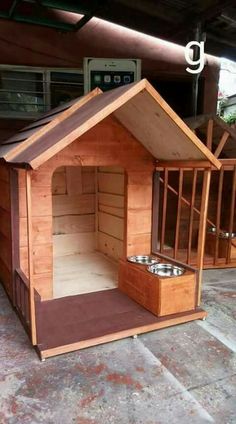 the dog house is made out of wood and has two bowls on top of it