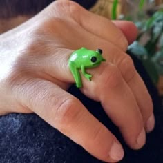 a person wearing a green frog ring with black eyes