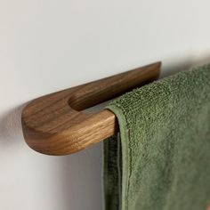 a green towel hanging on the wall next to a wooden rack with two wood handles