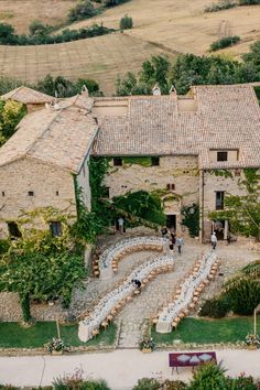 an aerial view of a stone building with white chairs set up in the front yard