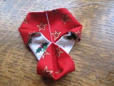 an origami christmas decoration on a wooden table with string attached to the neck