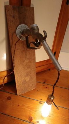 a light that is on top of a wooden floor next to a wall mounted lamp