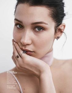 a young woman with piercings on her nose and hand under her chin looking at the camera