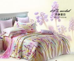 a bed with pink and yellow comforters on it in front of a white wall