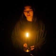 a woman holding a lit candle in her hands