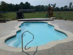 an empty swimming pool with steps leading up to the edge and a play area in the background