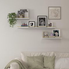 a living room with white couches and pictures on the wall above them, along with bookshelves