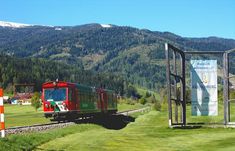 a red train traveling through a lush green countryside