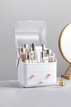 an open white box with cosmetics on it next to a mirror and gold faucet