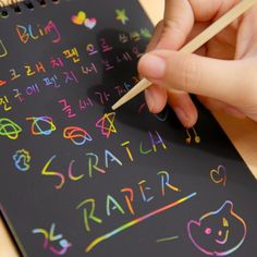 someone is writing on a blackboard with colored chalks